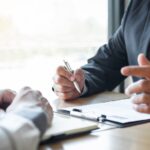 two people talking over documents on a table_s