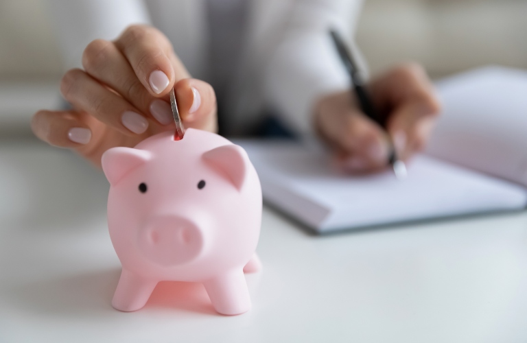 Someone putting money in a piggy bank