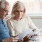 Old couple reviewing documents by a laptop_s