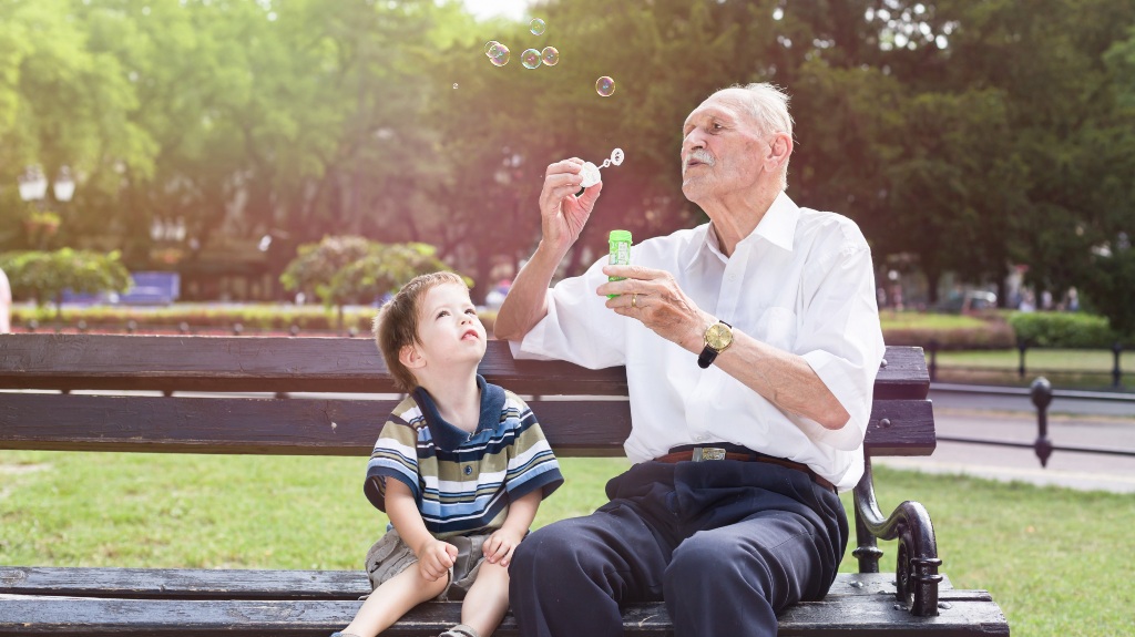 Old man blowing bubbles for a child