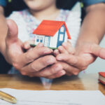 Hands,Holding,Small,House,After,Signing,Contract,concept,For,Real,Estate,insurance