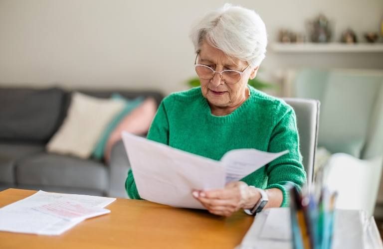 Senior woman sitting in the living room and doing paperwork